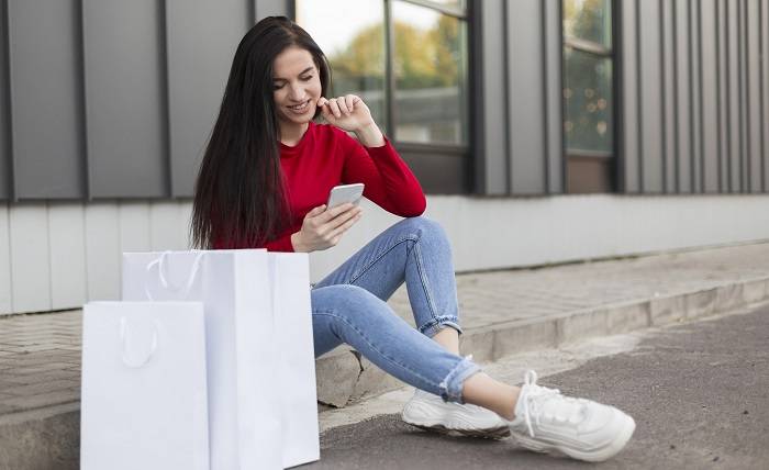 3 Reasons Why You Should Purchase Your Next Pair of Shoes from a Reputable Online Shop client red shirt sitting using her mobile phone